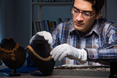 Young male jeweller working at night in his workshopの写真素材