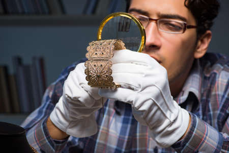 Young male jeweller working at night in his workshopの写真素材