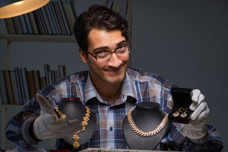 Young male jeweller working at night in his workshopの写真素材