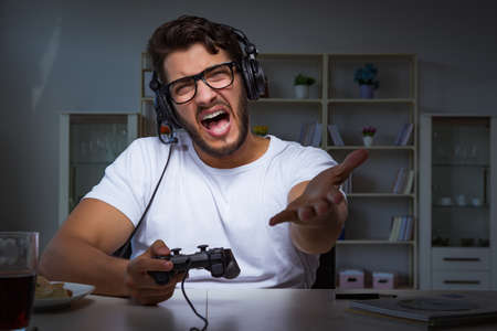 Young man playing games long hours late in the officeの写真素材