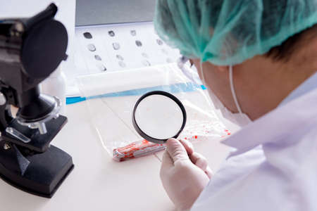 Criminologist police chemist looking at crime evidenceの写真素材