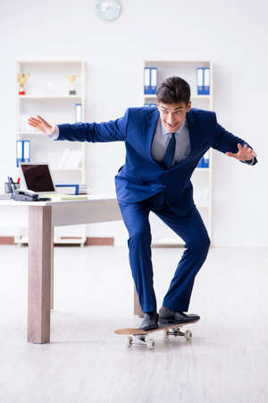 Young businessman with skate in office in sports conceptの写真素材
