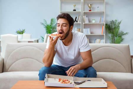 Man eating pizza having a takeaway at home relaxing restingの写真素材