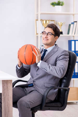 Young businessman playing basketball in office during breakの写真素材