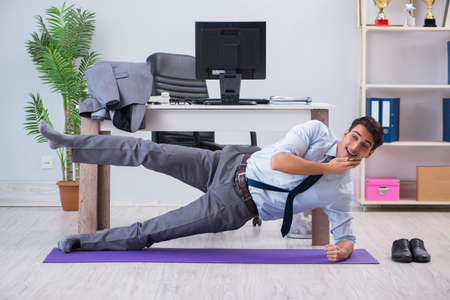 Businessman doing sports in office during breakの写真素材
