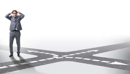 Young businessman at crossroads in uncertainty conceptの写真素材