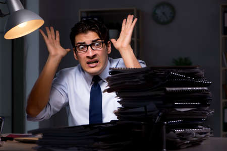 Young businessman working overtime late in officeの写真素材
