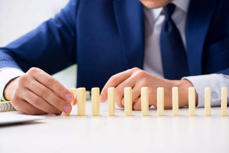 Young businessman playing with domino in officeの写真素材