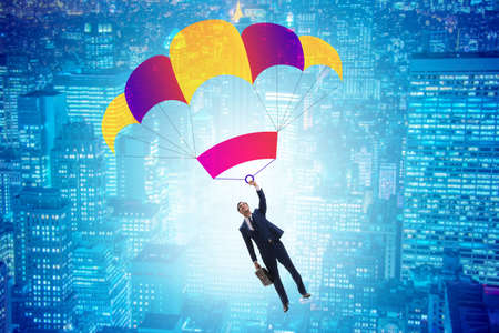 Young businessman falling on parachute in business conceptの写真素材