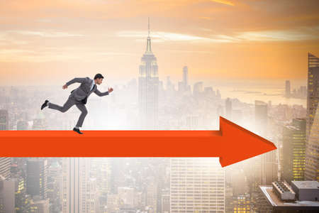 Businessman walking on arrow in business conceptの写真素材