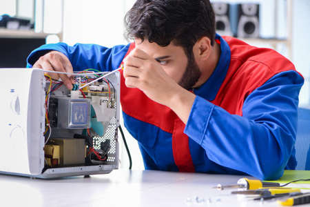 Young repairman fixing and repairing microwave ovenの写真素材
