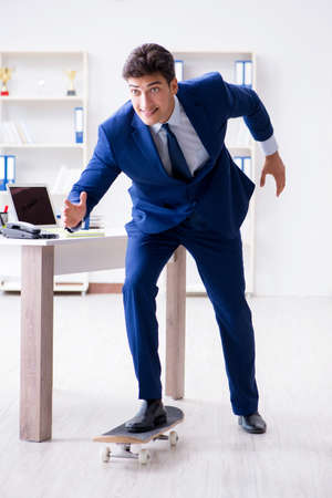 Young businessman with skate in office in sports conceptの写真素材