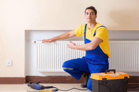Young repairman contractor repairing heating panelの写真素材