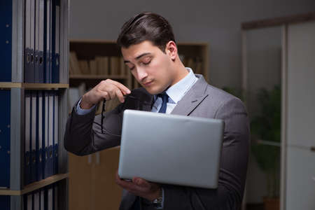 Businessman almost falling asleep working late hours in the officeの写真素材