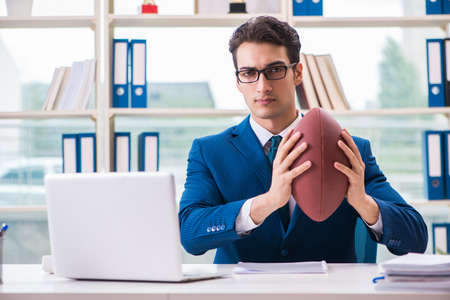 Businessman with american football in officeの写真素材