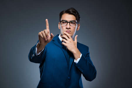 Businessman pressing virtual buttons on gray backgroundの写真素材