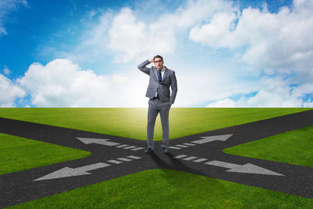 Young businessman at crossroads in uncertainty conceptの写真素材