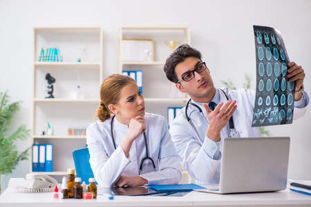 Two doctors examining x-ray images of patient for diagnosisの写真素材