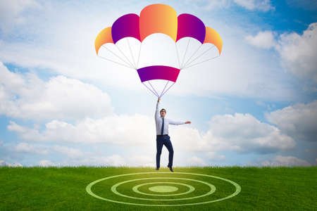 Young businessman falling on parachute in business conceptの写真素材