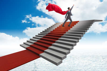 Superhero businessman climbing red carpet stairsの写真素材