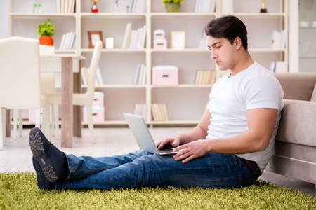 Man working on laptop at home on carpet floorの写真素材