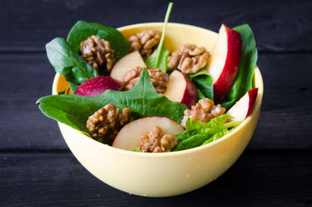 Spinach salad with nuts and apples served on tableの写真素材