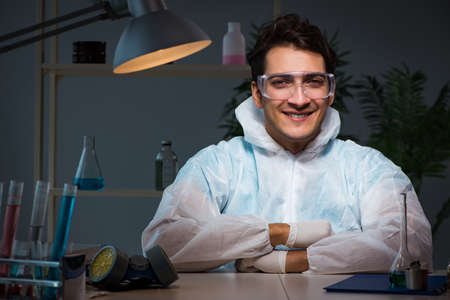 Young male lab chemist late at night in overtime time