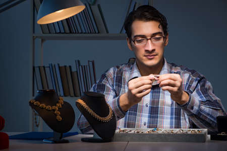 Young male jeweller working at night in his workshopの写真素材