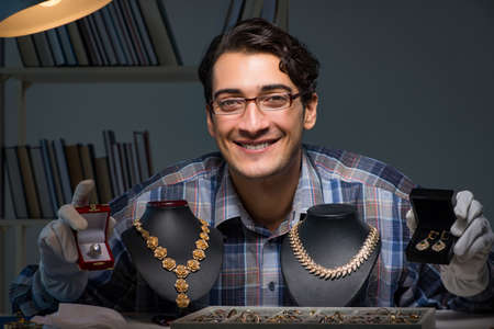 Young male jeweller working at night in his workshopの写真素材