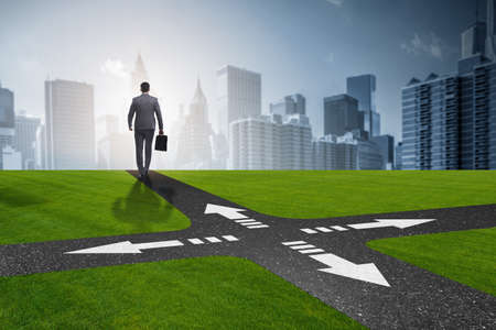 Young businessman at crossroads in uncertainty conceptの写真素材