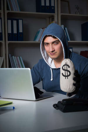 Young hacker hacking into computer at nightの写真素材