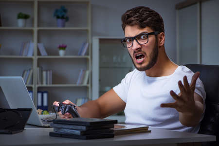 Young man playing games long hours late in the office