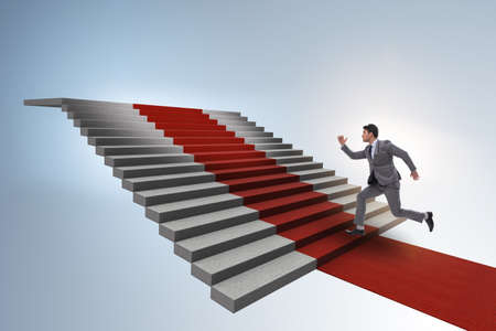 Young businessman climbing stairs and red carpetの写真素材