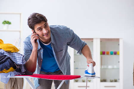 Young man husband doing clothing ironing at homeの写真素材