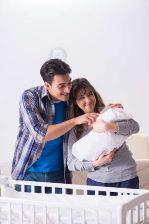 Young parents with their newborn baby near bed cotの写真素材