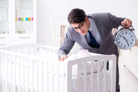 Young businessman trying to work from home caring after newbornの写真素材
