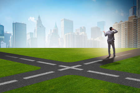 Young businessman at crossroads in uncertainty conceptの写真素材