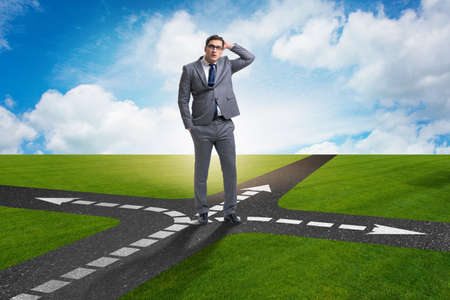 Young businessman at crossroads in uncertainty conceptの写真素材