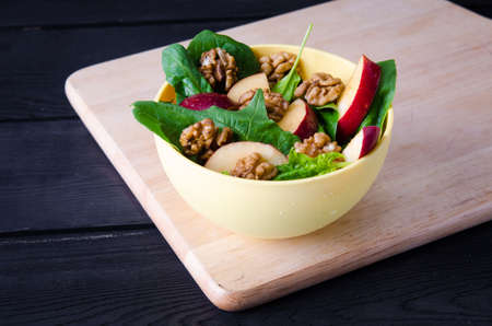 Spinach salad with nuts and apples served on tableの写真素材