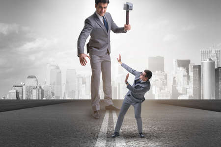 Bad angry boss threatening employee with hammerの写真素材