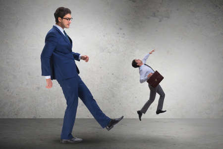 Bad angry boss kicking employee in business conceptの写真素材