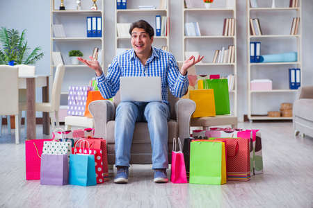 Young man after excessive shopping at homeの写真素材