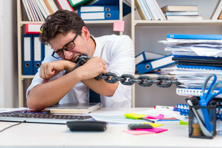 Employee attached and chained to his desk with chainの写真素材