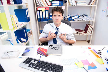 Employee attached and chained to his desk with chainの写真素材