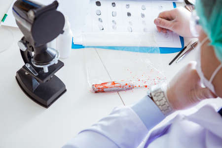 Criminologist police chemist looking at crime evidenceの写真素材
