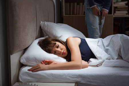 Burglar breaking into house at night to bedroom with sleeping womenの写真素材