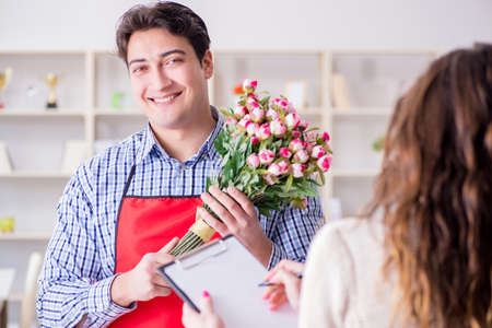Flower shop assistant selling flowers to female customerの写真素材