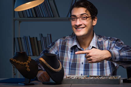 Young male jeweller working at night in his workshopの写真素材