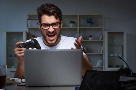 Young man playing games long hours late in the officeの写真素材
