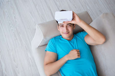 Young man wearing VR glasses relaxing on couch sofa